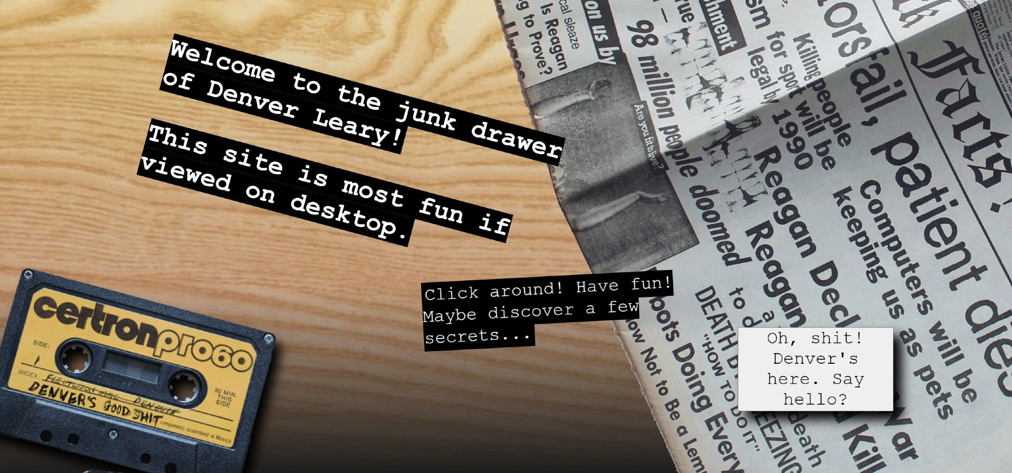 A screenshot of the "DENVER LEARY'S JUNK DRAWER" website. The visible text reads, "Welcome to the junk drawer of Denver Leary!
This site is most fun if viewed on desktop.
Click around! Have fun! Maybe discover a few secrets..."
overlaid a wood background with a cassette tape and satire newspaper from a Dead Kennedys album.